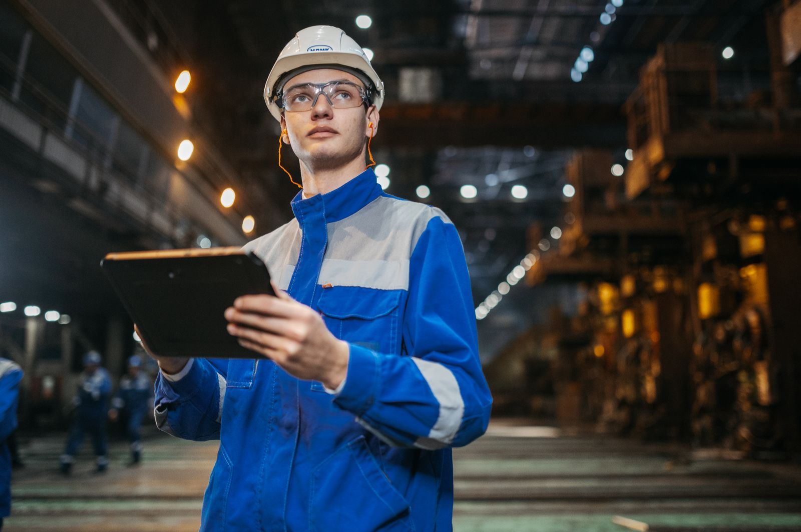Ingeniero con casco y tablet en una planta industrial